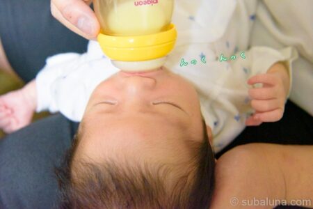 パパの膝上でミルクを飲む赤ちゃん